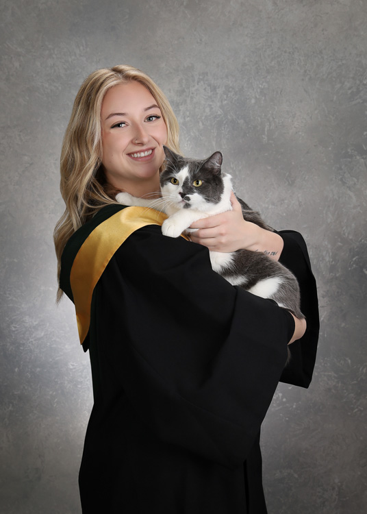 female graduate holding a grey and white cat with both of them looking at the camera