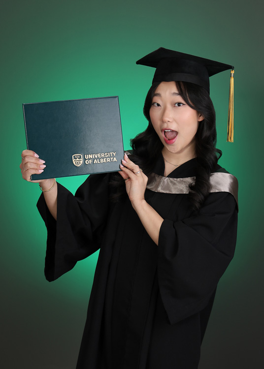 female graduate holding up her degree holder while gasping
